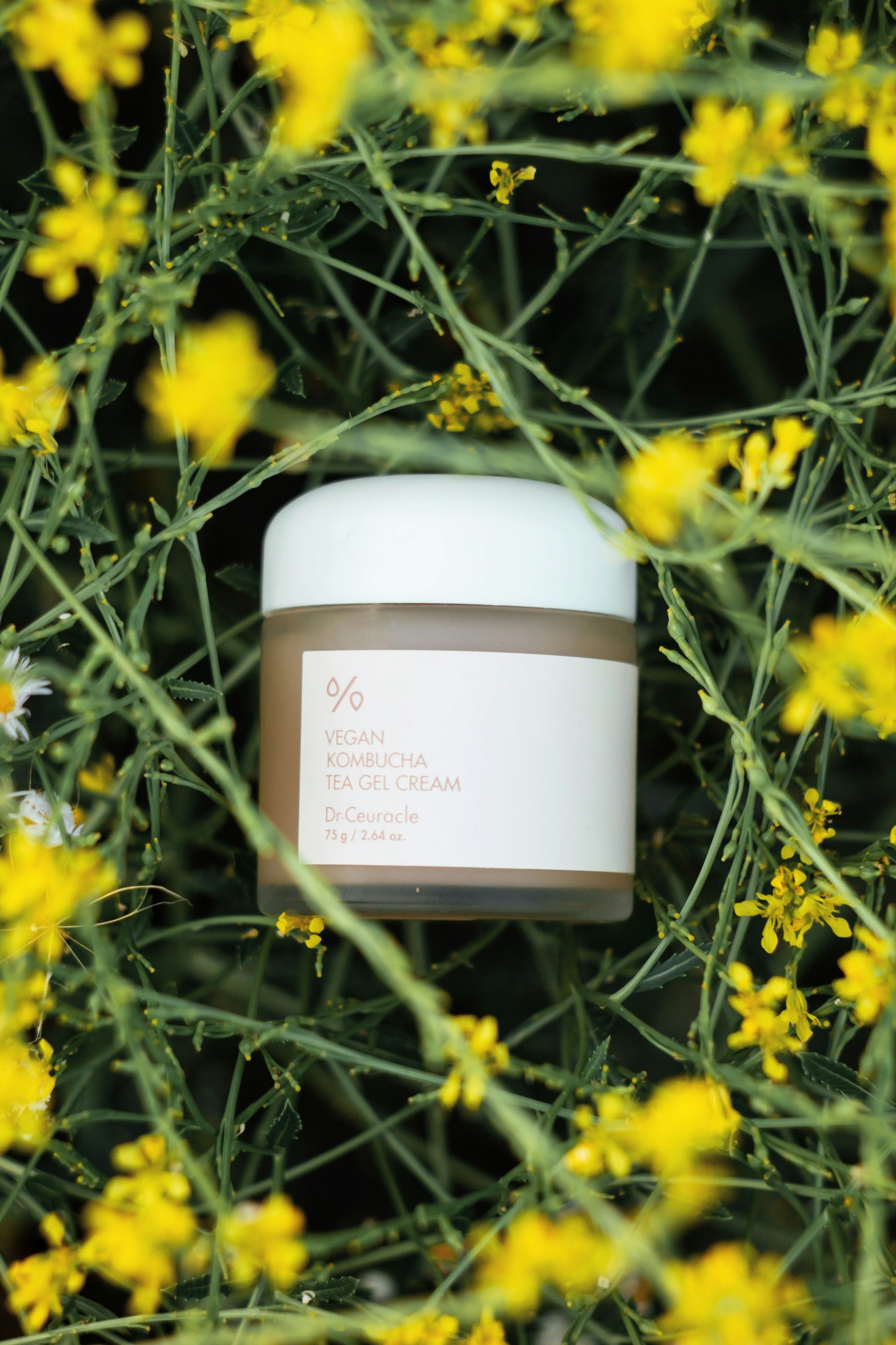 a jar of cream sitting in a field of yellow flowers